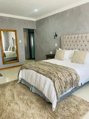 a bedroom with a large bed and a mirror at Kruger Place in Mokopane