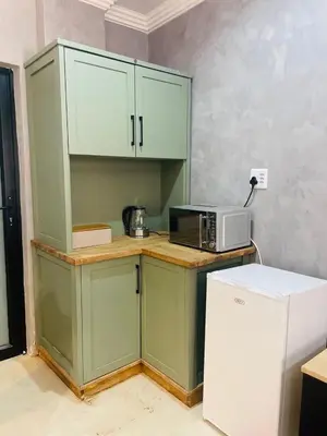 a kitchen with green cabinets and a microwave at Kruger Place in Mokopane