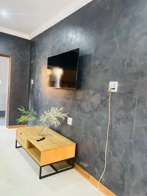 a living room with a table and a tv on a wall at Kruger Place in Mokopane