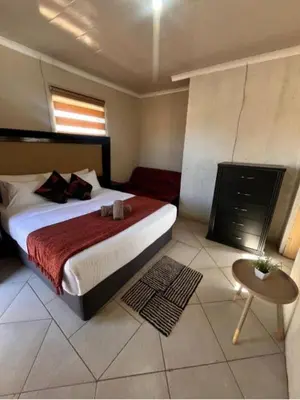 a bedroom with a large bed and a table at BEGIN GUESTHOUSe in Ermelo