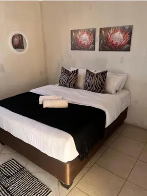 a large bed in a room with two pictures on the wall at BEGIN GUESTHOUSe in Ermelo