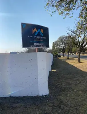 a sign for a park next to a white wall at BEGIN GUESTHOUSe in Ermelo