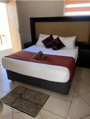 a bedroom with a large bed with two slippers on it at BEGIN GUESTHOUSe in Ermelo