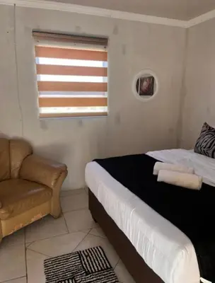 a bedroom with a bed and a couch and a window at BEGIN GUESTHOUSe in Ermelo