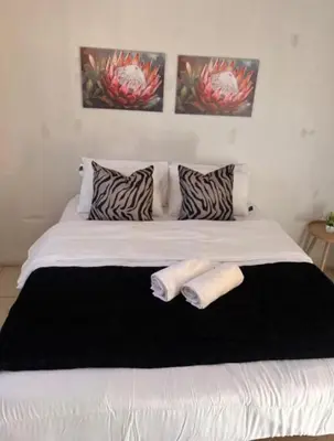 a white bed with two towels on top of it at BEGIN GUESTHOUSe in Ermelo