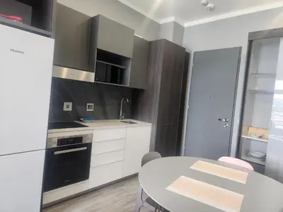 a kitchen with white cabinets and a table and a sink at Menlyn Maine Residences 1317 in Pretoria