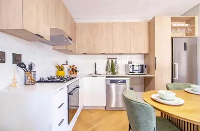 a kitchen with white cabinets and a table with chairs at Madumane Self Catering in Hildreth Ridge