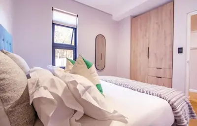 a bedroom with a bed with white sheets and a window at Madumane Self Catering in Hildreth Ridge
