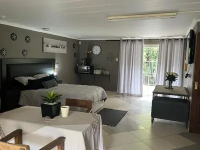 a bedroom with two beds and a table and a window at Cloete Self catering Guest room in Ermelo