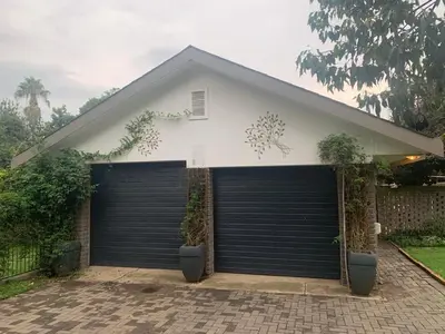 a garage with two garage doors in front of a house at Cloete Self catering Guest room in Ermelo