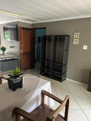 a living room with a couch and a table and a chair at Cloete Self catering Guest room in Ermelo