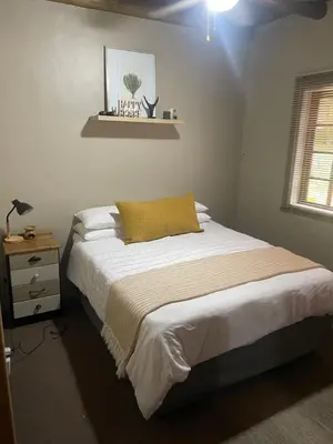 a bedroom with a bed with a yellow pillow on it at Botterblom Hide-Away in Sabie