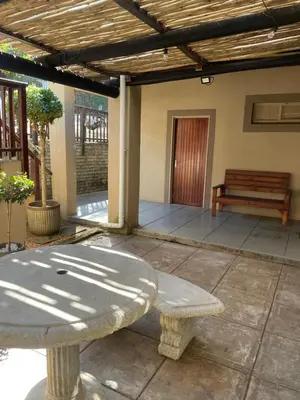 a patio with a table and a bench on a porch at Botterblom Hide-Away in Sabie