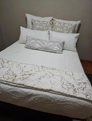 a bed with a white comforter and pillows at The Loraine Luxury Villa in Witbank