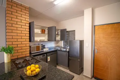a kitchen with stainless steel appliances and a bowl of fruit on a counter at The Place at Waterfall in Midrand