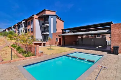 a swimming pool in front of a building at The Place at Waterfall in Midrand