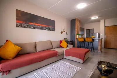 a living room with a couch with red and yellow pillows at The Place at Waterfall in Midrand