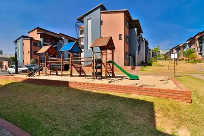 a playground with a slide and a swing set at The Place at Waterfall in Midrand