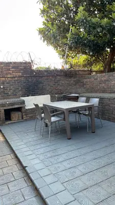 a picnic table and chairs on a patio with a brick wall at Aneiwa airport lodge in Kempton Park
