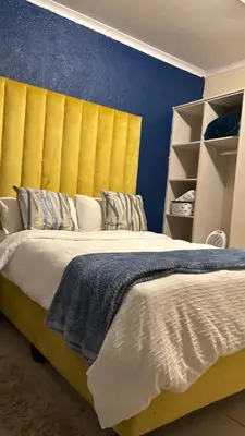 a bedroom with a large bed with a yellow headboard at Aneiwa airport lodge in Kempton Park