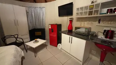 a small kitchen with a red refrigerator and a table at Aneiwa airport lodge in Kempton Park