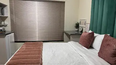 a bedroom with a large bed and a large window at Aneiwa airport lodge in Kempton Park