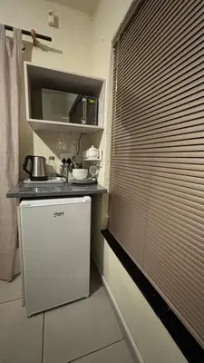 a small kitchen with a sink and a window with blinds at Aneiwa airport lodge in Kempton Park