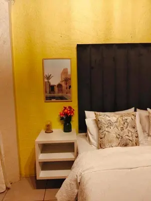 a bed with a black headboard and a table with flowers at Aneiwa airport lodge in Kempton Park