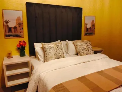 a bedroom with a large bed with a black headboard at Aneiwa airport lodge in Kempton Park