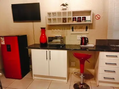 a kitchen with a red refrigerator and a red stool at Aneiwa airport lodge in Kempton Park