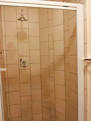 a shower in a bathroom with white tiles at Aneiwa airport lodge in Kempton Park