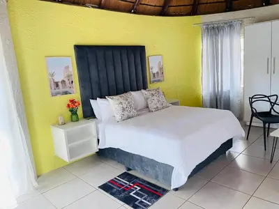 a bedroom with a bed and a yellow wall at Aneiwa airport lodge in Kempton Park