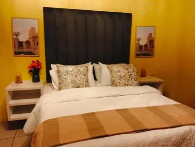 a bedroom with a bed with a black headboard and pillows at Aneiwa airport lodge in Kempton Park
