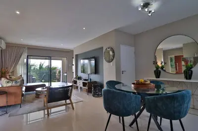 a living room with a table and blue chairs at Perfect Hideaway in Nelspruit