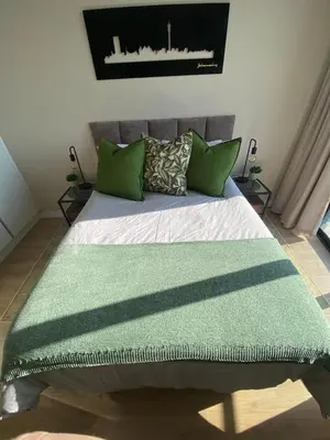 a bed with green pillows and a green rug on it at Stunning 2 bedroom condo at Ellipse Midrand in Midrand
