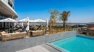 a swimming pool with tables and umbrellas on a building at Stunning 2 bedroom condo at Ellipse Midrand in Midrand