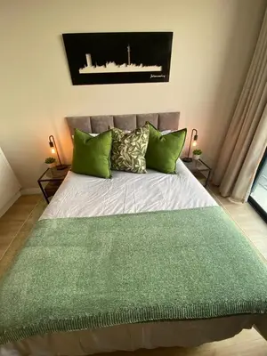 a bedroom with a large bed with green pillows at Stunning 2 bedroom condo at Ellipse Midrand in Midrand