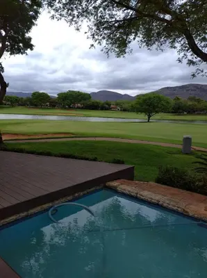 a swimming pool with a view of a golf course at Pecanwood Relaxing Villa - Golf, Pool, Braai & Dam Views in Hartbeespoort