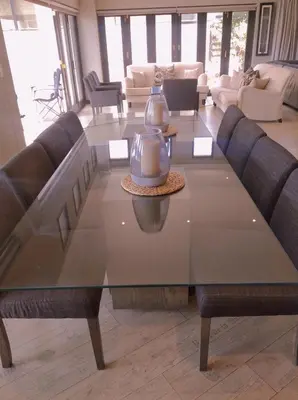a large glass table with chairs and a living room at Pecanwood Relaxing Villa - Golf, Pool, Braai & Dam Views in Hartbeespoort