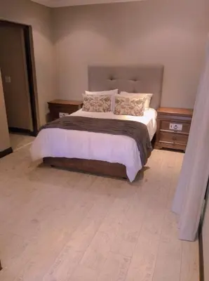 a bedroom with a bed with white sheets and pillows at Pecanwood Relaxing Villa - Golf, Pool, Braai & Dam Views in Hartbeespoort