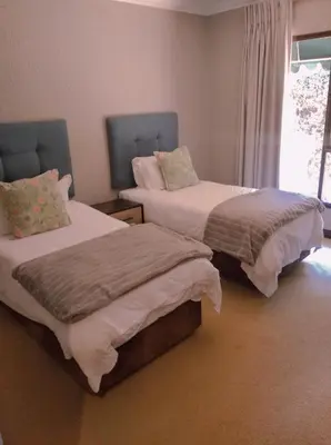 two beds sitting next to each other in a bedroom at Pecanwood Relaxing Villa - Golf, Pool, Braai & Dam Views in Hartbeespoort