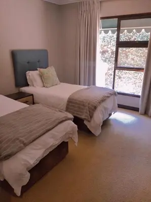 a bedroom with two beds and a window at Pecanwood Relaxing Villa - Golf, Pool, Braai & Dam Views in Hartbeespoort