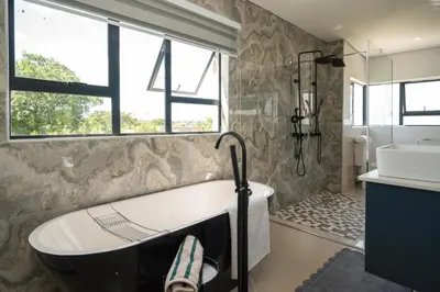 a bathroom with a bath tub and a sink at Grace House, Mkhuhlu, spacious 4-bedroom house in Belfast