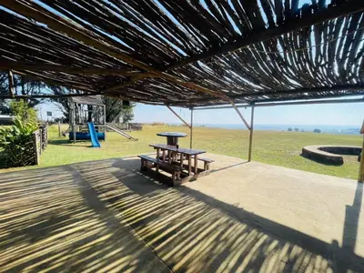 a picnic table under a straw roof with a playground at Stonehouse in Carolina