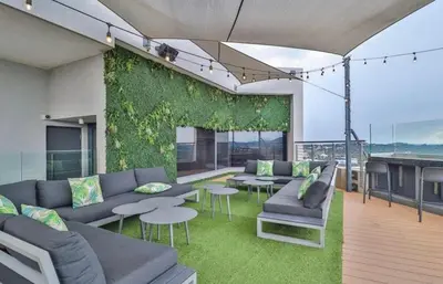 a living room with couches and tables and a green wall at Luxury AT Maine in Pretoria