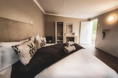 a bedroom with a large bed with a stuffed animal on it at Die Skoen in Dinokeng Game Reserve
