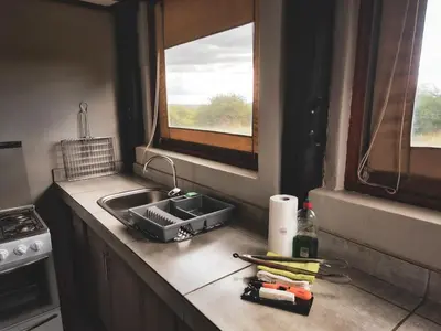 a kitchen counter with a sink and two windows at Die Skoen in Dinokeng Game Reserve