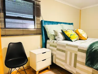 a bedroom with a bed and a black chair at The Man Cave in Sabie