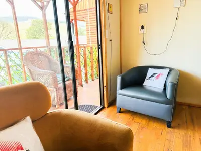 a living room with a couch and a chair on a porch at The Man Cave in Sabie