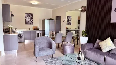 a living room with a couch and a table with chairs at Forest Haven in Midrand